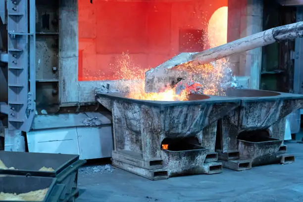 skimming melted aluminum for removing the dross before casting. Aluminum foundry works showing an open furnace